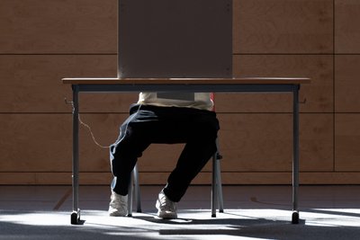 Ein Mann sitzt in einer Wahlkabine: Warum gehen manche nicht wählen?