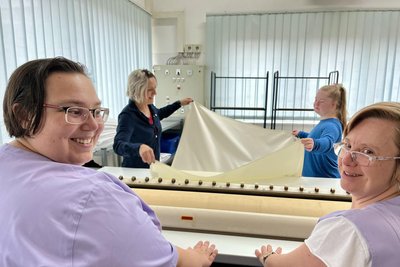 Schichtwechsel: Annabell Riedel (l.) und Maika Krajewski (v.) haben gut Lachen: Sie beherrschen die Bügelmaschine. Annika Renatus (hinten r.) weist Jana Leischker ein.