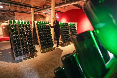 Eine Frau rüttelt zum Test Sektflaschen in der Erlebniswelt des Sektherstellers Rotkäppchen-Mumm in Freyburg (Unstrut).