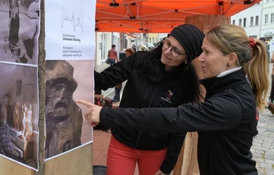 Damaris Günther-Schmidt (l.) und Doreen Burgold betrachten die Vorlage für die Holzfigur, an der Johannes Düring am Freitag auf dem Schneeberger Markt geschnitzt hat.