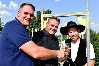1,8 Millionen Euro: Schreinerei und Metallbau Wagner aus Niederwürschnitz investiert in Halle für Fensterbau - Die Geschäftsführer Steve und Sören Wagner mit Simon Meyer von der Firma Holzbau Meyer (v. l.) stießen auf dem Gerüst an.
