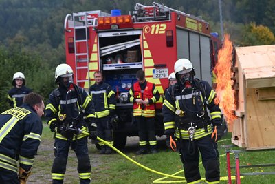 Heiße Vorführung zum 140. Feuerwehr-Geburtstag in Falkenau: Ein Modell dient dazu, Brandphasen darzustellen. Philipp Schaarschmidt (l.) ist der Erklärer.