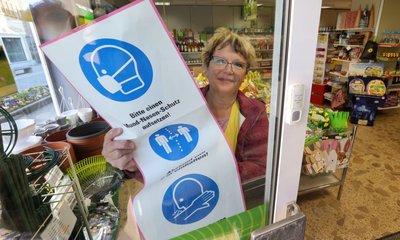 Der Mund-Nasen-Schutz ist nicht mehr Pflicht. Sparland-Mitarbeiterin Cornelia Eismann entfernt das entsprechende Plakat. 