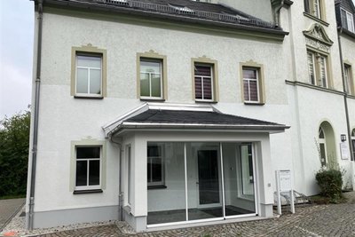 Blick von der Hauptstraße in Hohndorf auf den Eingang zur sanierten Praxis im Erdgeschoss. Rechts daneben praktiziert eine Allgemeinärztin.