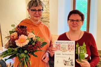 1000. Klöpplerin im Schloss begrüßt - Steffi Greisner aus Dessau-Roßlau (r.) ist von Simone Georgi, der Leiterin der Volkskunstschule des Landkreises, überrascht worden.