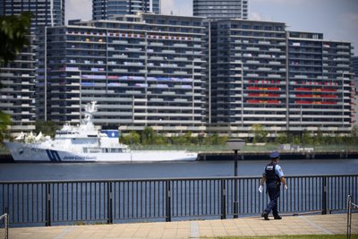 Ein  Polizist patrouilliert vor einem Boot der japanischen Küstenwache vor dem Olympic Village . Das olympische Dorf ist eine Wohnsiedlung, in der die Teilnehmer der Olympischen Spiele 2020 untergebracht sind. 