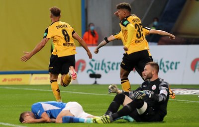 Die Rostocker Nico Neidhart (vorn l-r) und Markus Kolke sind geschlagen am Boden, während der Dresdner Torschütze Heinz Robert Mörschel (hinten l-r) mit seinen Mannschaftskameraden Ransford-Yeboah Königsdörffer und Julius Kade (verdeckt) über das 1:0 jubelt.