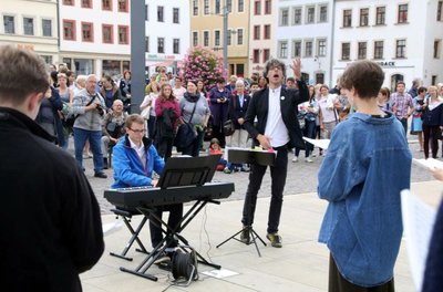 Domkantor Albrecht Koch (M.) dirigiert die Jugendkantorei des Freiberger Domes auf dem Obermarkt. 