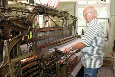 Manfred Fierke, ehemaliger Beschäftigter der Tuchfabrik, führt einen der historischen Webstühle vor.