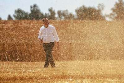 Agrarminister Wolfram Günther geht bei Kitzscher durch Erntestaub über ein Feld mit Wintergerste. 