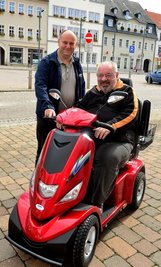 Uwe Sommerfeldt aus Frankenberg mit seinem neuen Rollstuhl-Fahrzeug, übergeben von Lutz Dick (l.) von Reha-aktiv aus Chemnitz.
