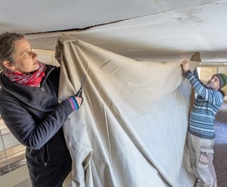Die Restauratoren Sandra Finsterbusch und Jens Wirth erneuern die Leinwand-Papier-Bespannung der Emporen in der Stadtkirche Treuen.
