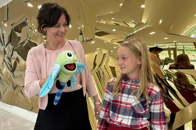 An der Hand von Theresa Lemser erklärt Libelle Billie der Schülerin Katja Stöcker die Arbeit im Zentrum für effiziente Hochtemperaturstoffumwandlung an der Winklerstraße in Freiberg. Im Hintergrund ist die Installation „Solaris“ zu sehen.