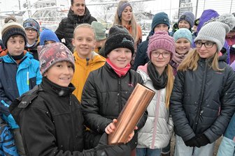 12-Millionen-Euro-Campus im Erzgebirge: Sporthalle wird nun gebaut - doch Kinder lernen weiter in Containern - Auch eine Schulklasse war bei Schnee und eisigen Temperaturen zum Spatenstich gekommen: Arne Vincent Weigert (l.) und Lotta Schacht (2. v. l.) halten die Zeitkapsel, die bei solchen Anlässen nicht fehlen darf, in den Händen.