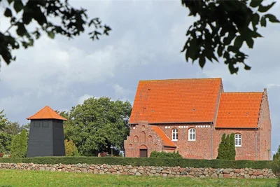 Die Kirche in Holeby mit romanischem Altarraum, gotischer Vorhalle und einem Glockenturm, der daneben steht.