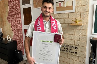 Serdar Sido in seinem Wohnzimmer, in dem sein Meisterbrief an der Wand hängt. Ebenso stolz ist er auf seinen deutschen Pass, den er seit zwei Jahren besitzt.