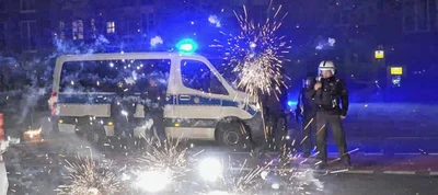 Polizeibeamte stehen in Berlin hinter explodierendem Feuerwerk. Nach Angriffen auf Einsatzkräfte in der Silvesternacht hat die Diskussion um Konsequenzen begonnen.