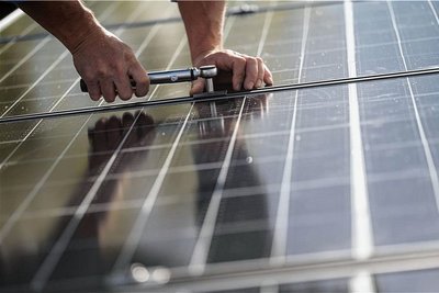 Mitarbeiter einer Firma montieren Fotovoltaikmodule auf dem Dach eines Hauses (Symbolbild). 