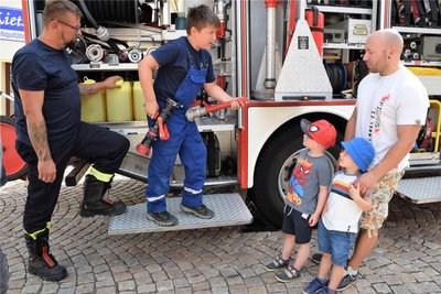 Faszination Jugendfeuerwehr: Simon erklärt Enrico Fröhlich sowie den Kindern Emil und Kurt, wie ein Strahlrohr funktioniert. Links im Bild Jugendgruppenleiter Ralf Goldhardt.