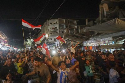 Menschen schwenke agyptische Flaggen und verfolgen im zentralen Gazastreifen das WM-Spiel Ägypten gegen Belgien auf einer Großbildleinwand.