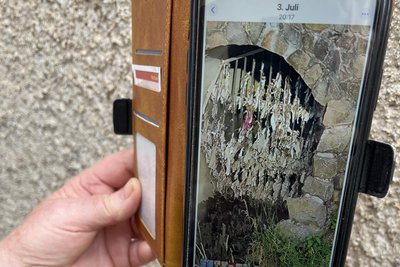 Anwohnerin Heidi Stiegler zeigt auf dem Handy am 3. Juli den Einlauf, als sich besonders viel Toilettenpapier im Gitter befand. Laut AZV wird das Papier regelmäßig entfernt.