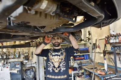 Amin Ali Sofi wechselt an der Vorderachse eines Wagens einen Stabilisator.