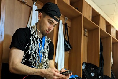 Ein Moment der Ruhe nach dem gewonnen Finale im Fiba Europe Cup: Wes Van Beck, Spieler der Niners Chemnitz, in der Umkleidekabine mit Goldmedaille, Netz vom Korb und Handy in der Hand.
