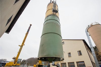Ein Kran hat das Kalksilo am Haken und hebt das rund 15 Meter große und zwölf Tonnen schwere Teil aus dem Gebäude. Zur Entwässerung wurde den Pressen früher Kalk zugesetzt, um damit einen größeren Grad der Entwässerung des Klärschlamms zu erreichen.