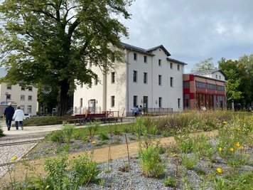 Das umgebaute Bahnhofsgebäude aus Richtung Stadtpark gesehen. Wo einst die Züge entlang fuhren, blüht und grünt es heute.