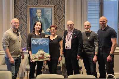 Die Eisschwimmer aus Mittelsachsen übergeben das Kunstwerk von Uwe Schwarz im Rathaus Oulu. Mit im Bild: Oulus Verwaltungsdirektor Ari Heikkinen und Geschäftsführerin von Oulu2026 Piia Rantala-Korhonen. Die finnische Stadt ist Europas Kulturhauptstadt 2026, Chemnitz war es 2025.