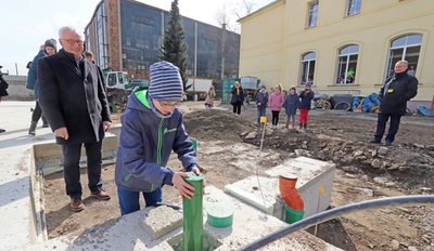Finlay Schwenke darf die Zeitkapsel in den Grundstein des Hort-Neubaus an der Grundschule Halsbrücke senken. Bürgermeister Andreas Beger (l.) schaut zu, ob alles gut klappt. 