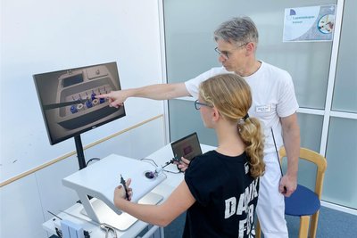 Oberarzt Dr. Marian Fenik erklärt der 13-jährigen Tessa Krellmann die Handhabung des Laparoskopietrainers, der einen minimalinvasiven Eingriff im Bauchraum simulieren soll.