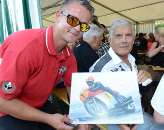 Matthias Hinkel aus Bad Schlema (links) mitten in der Glückseligkeit: Beim Dreieckrennen in Zschorlau nutzte der Motorsportfan seine Chance, um sich von Weltstar Giacomo Agostini ein Autogramm zu holen.
