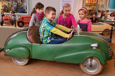 Ben aus Gelenau hat sichtlich Spaß an einem Tretauto, das er im Pohl-Ströher-Depot Leni, Hanna und Linda (v.l.) vorführt. Das Kinderfahrzeug ist das Gesellenstück eines Zwickauer Karosserieklempners, das er 1954 konstruierte und baute. Da er noch im gleichen Jahr in den Westen ging, wusste er nichts über den Verbleib des Autos. Jetzt hat er es wiedergefunden.