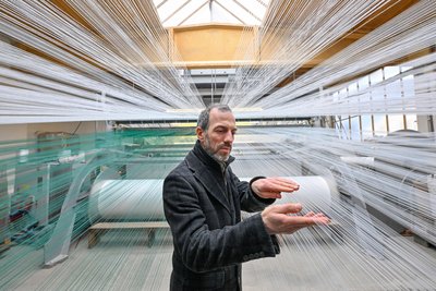 Jens Reindl, Geschäftsführer der Firma Mr. Snow, zwischen 12.000 Kunststofffäden, die in eine Webmaschine führen.