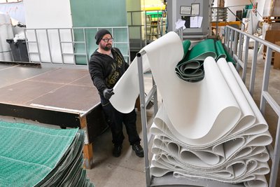 Mitarbeiter Rico Neumann schneidet die Kunststoffbahnen auf die gewünschte Größe.