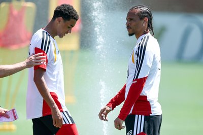 Jamal Musiala und Leroy Sané freuen sich über den Wassersprenger. 