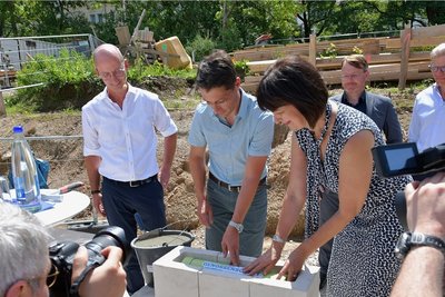 Mirijam Luserke vom Verband Sächsischer Wohnungsgenossenschaften und André Kolmschlag legten die Hülse mit Zeitdokumenten in den Grundstein. Sie enthält unter anderem Baupläne, gültige Münzen und eine Tageszeitung. Im Hintergrund von links: Thomas Buckreus, Vorstandschef der Freiberger Genossenschaft, Oberbürgermeister Sven Krüger und Architekt Axel Ruhsam.
