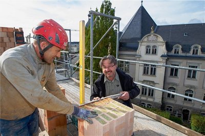 Bauunternehmer Christian Zschögner (rechts) und Jens Zschögner, Polier der Greizer Firma Taubert-Bau, haben gut lachen, denn der Aufbau des letzten Geschosses der ehemaligen Kommandantur befindet sich auf der Zielgeraden. Nun kann das Flachdach aufgesetzt werden. Im Hintergrund: das Ex-Landratsamt. 