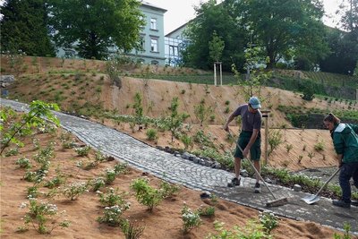 Frank Schreiter und Klara Kluge füllen die Fugen zwischen den Pflastersteinen des neuen Weges, der durch den Seminargarten führt. 