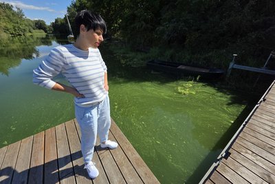Cassy Wettengel, Leiterin der Jugendherberge Taltitz, schaut am Bootssteg der Jugendherberge auf das mit Blaualgen belastete Wasser.