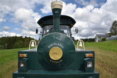 Der Schriftzug der Vogtland-Express-Kleinbahn am Führerhaus der Lokomotive auf Rädern.