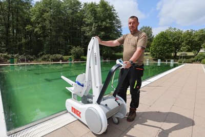 Schwimmmeister Andreas Meirich zeigt den mobilen Schwimmbadlifter, der Menschen im Erlebnisbad Mannichswalde dabei hilft, ins Wasser und wieder herauszukommen.