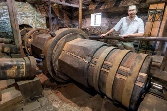 170.000 Euro für den Kupferhammer: Stadt Olbernhau rettet ihr Welterbe vor dem Verfall - Museumsleiter Lasse Eggers steht hinter der rund 9,5 Meter langen Welle, die die drei Hämmer antreibt und die erneuert werden muss.