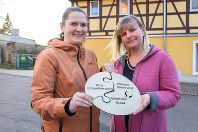 Zwei Mütter zeigen ein Puzzle, das die Kitas in Erlau symbolisch miteinander verbindet.