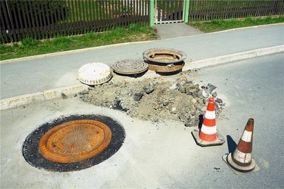 Auf der Querstraße muss eine defekte Schachtabdeckung repariert werden.