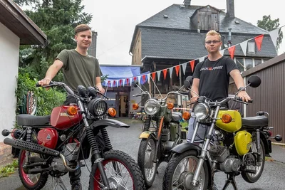 Phillip Schettler (links) mit zwei von ihm aufgebauten Simson sowie einer früher von der Gesellschaft für Sport und Technik (GST) genutzten MZ. Sein Freund Patrick Lumm schraubt ebenfalls gern. Hinten das Haus des Uropas, das Phillip später gern sanieren lassen möchte. 