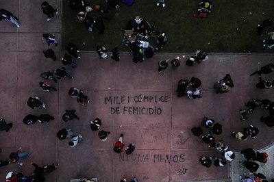 Demonstranten gehen in Buenos Aires in der Nähe eines Schriftzugs "Milei femicide accomplice" (Milei Frauenmord Mittäter), der sich auf Präsident Javier Milei bezieht, während eines Marsches zum Jahrestag der Frauenbewegung "Ni Una Menos" (Nicht eine weniger).