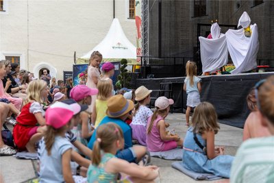 Gespannt lauschen die Kinder dem, was auf der Bühne im Schlosshof vor sich geht.