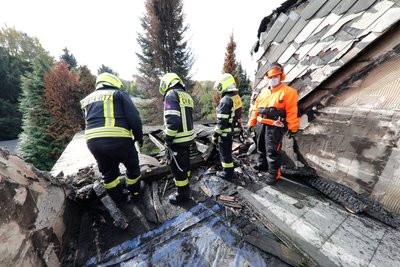 Feuerwehrleute im ausgebrannten Obergeschoss des Hauses in Rabenstein. Das Dach soll nun winterfest gemacht werden.